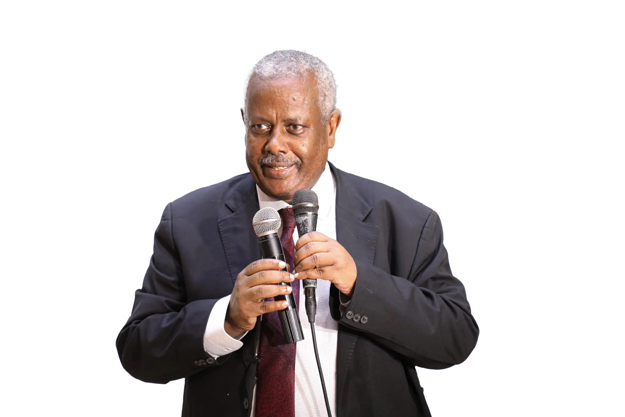 Speaker in a suit addressing an audience with two microphones